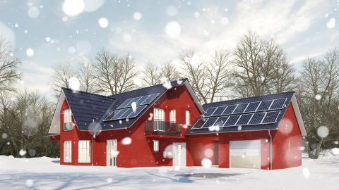 Ein Haus im Winter bei Schneefall und Kälte mit einer Photovoltaikanlage auf dem Dach zum Heizen.